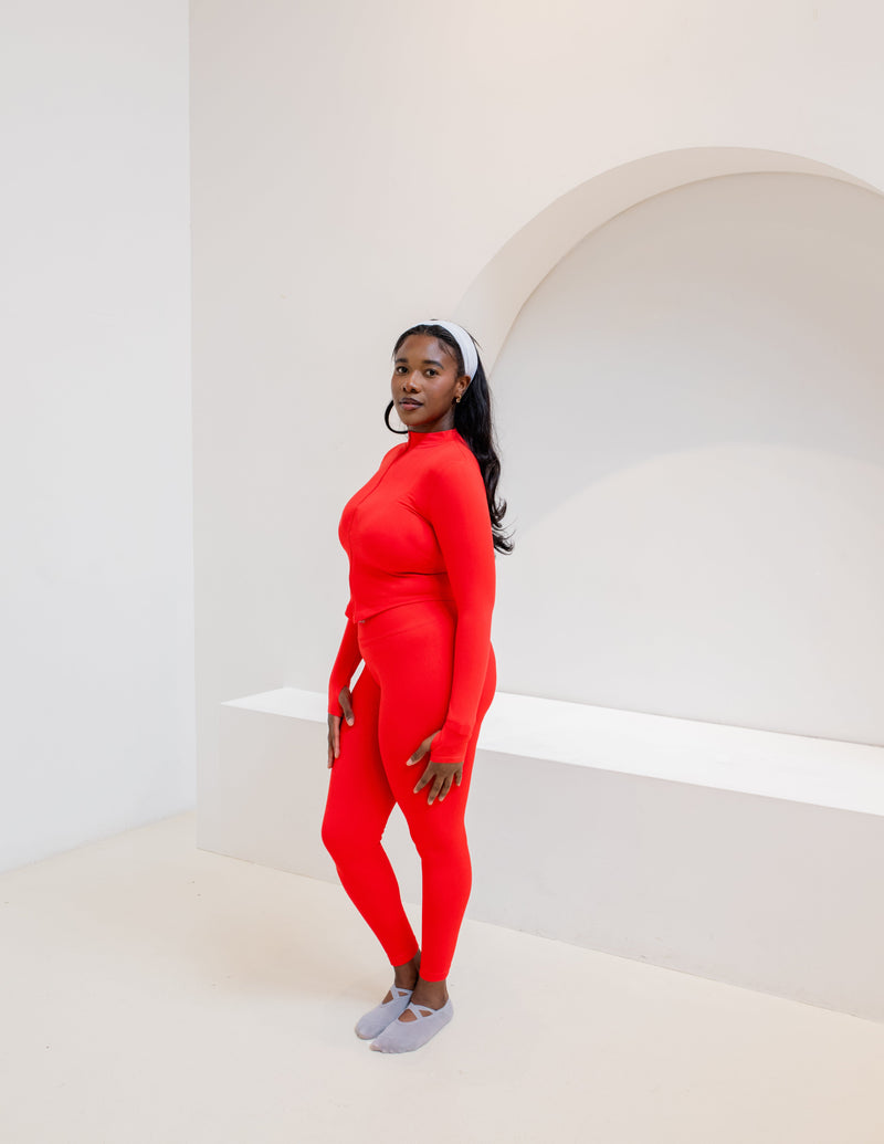 Woman wearing the SaturSculpt Scarlet Red Sculpt Set, a cropped zip jacket and high-waisted leggings