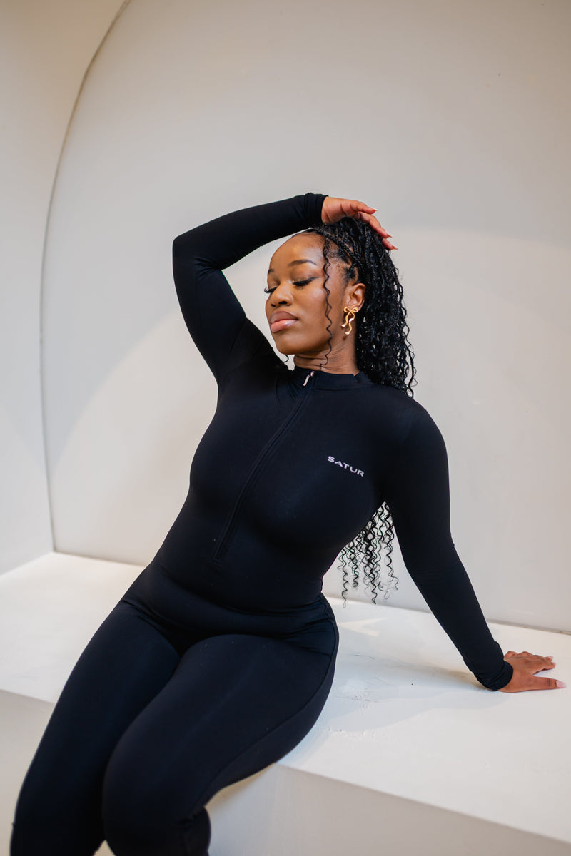 Woman wearing the SaturSculpt Midnight Black Flare Jumpsuit with long sleeves and a flared leg